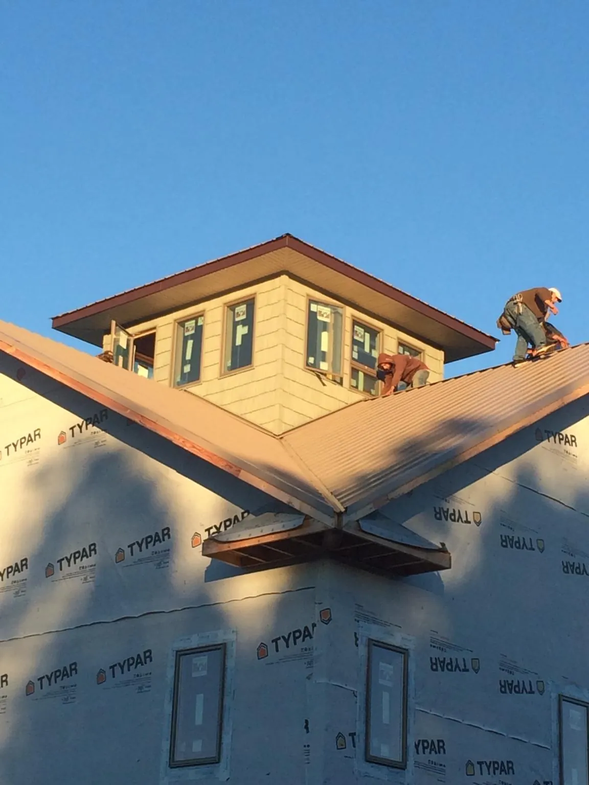 Roofers working around a rooftop cupola on a new metal roof at sunset — Roof Waterproofing in Saint Marys by Roofing Brothers